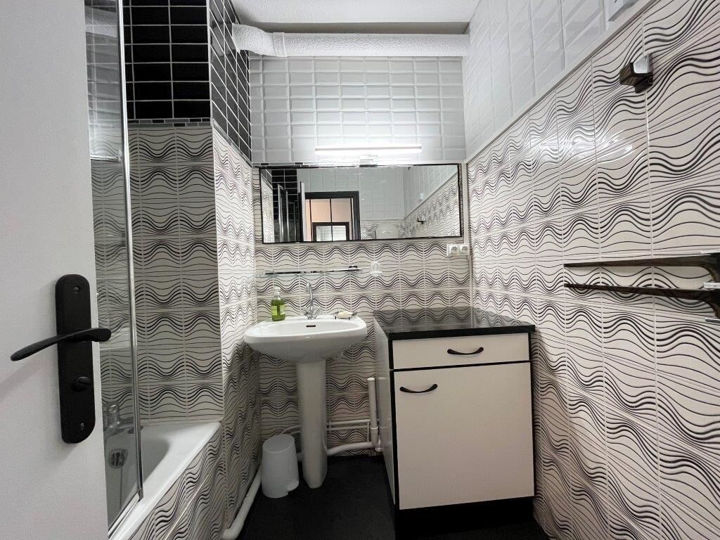 Ein Badezimmer mit einem weißen Waschbecken, einem Spiegel, einem weißen Schrank und einer Duschkabine.