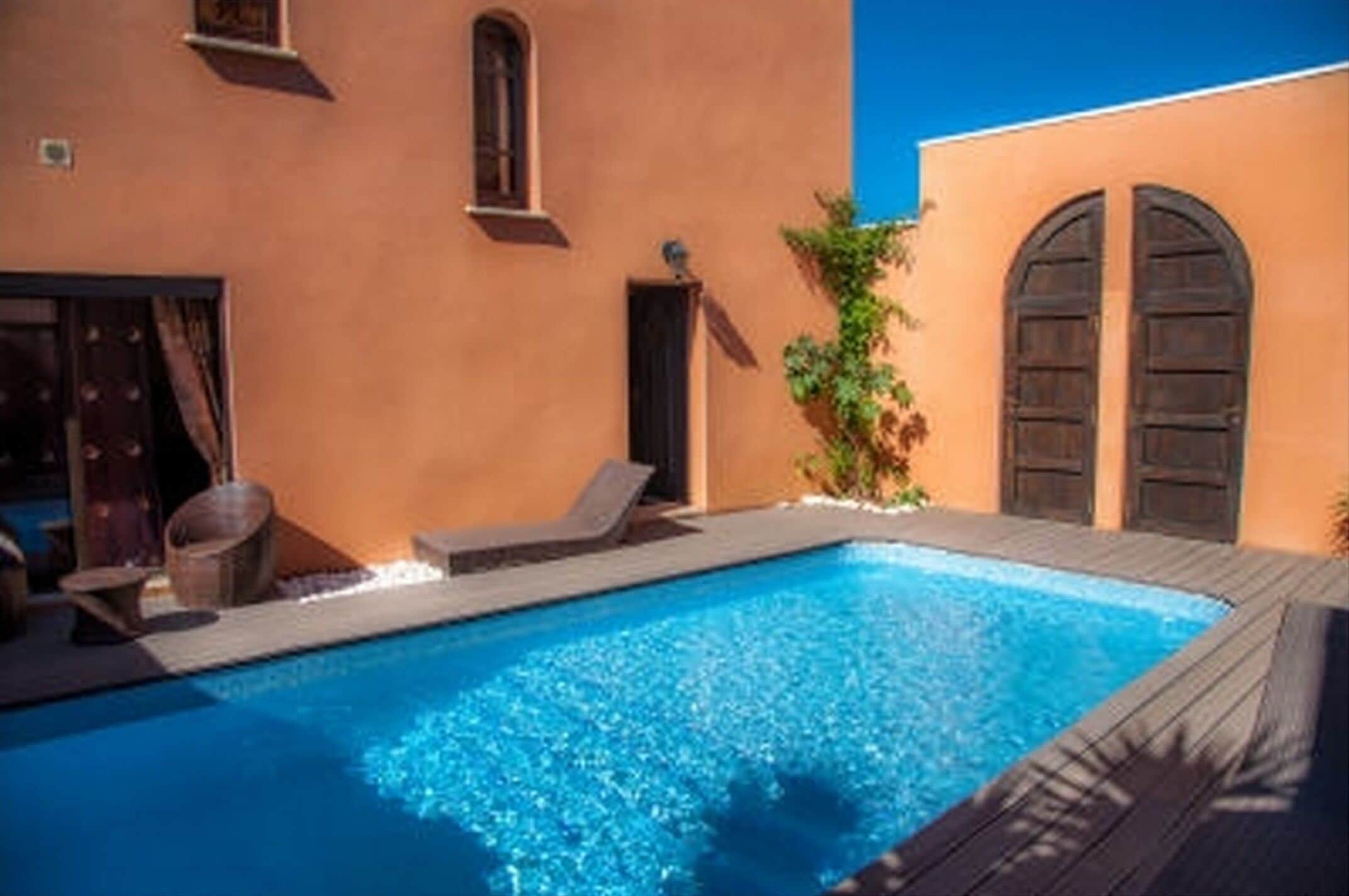 Une piscine avec des chaises longues et une terrasse en bois.