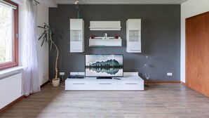 A modern living room with a flat-screen TV, white cabinetry, and a large potted plant. - Vacation home Haus am Deich in Reußenköge for up to 6 people (Reußenköge)