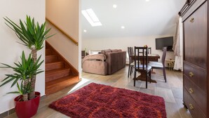 A staircase leading to a living area with a sofa, a dining table, and a potted plant. - Apartment Ivana (Dubrovnik)