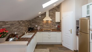 A modern kitchen with white cabinets, a wooden countertop, a built-in oven, and a skylight. - Apartment Ivana (Dubrovnik)