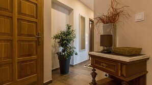 A hallway with a wooden door, a potted plant, a lamp, and a small table with a basket. - Apartment Ivana (Dubrovnik)