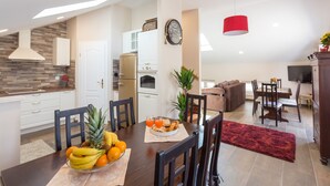 A modern kitchen with white cabinets, a built-in oven, and a red pendant light. - Apartment Ivana (Dubrovnik)