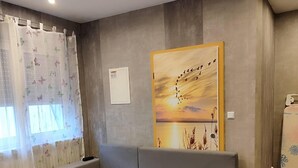 A modern living room with a grey sectional sofa, a round wooden coffee table, and a large landscape painting on the wall.