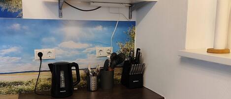 A kitchenette with a microwave, coffee maker, and knife block on the countertop.