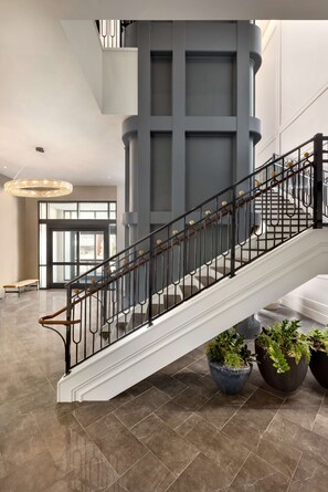 A modern interior with a staircase, potted plants, and a large window. - Valley Hotel Homewood Birmingham, Curio Collection by Hilton (Birmingham)
