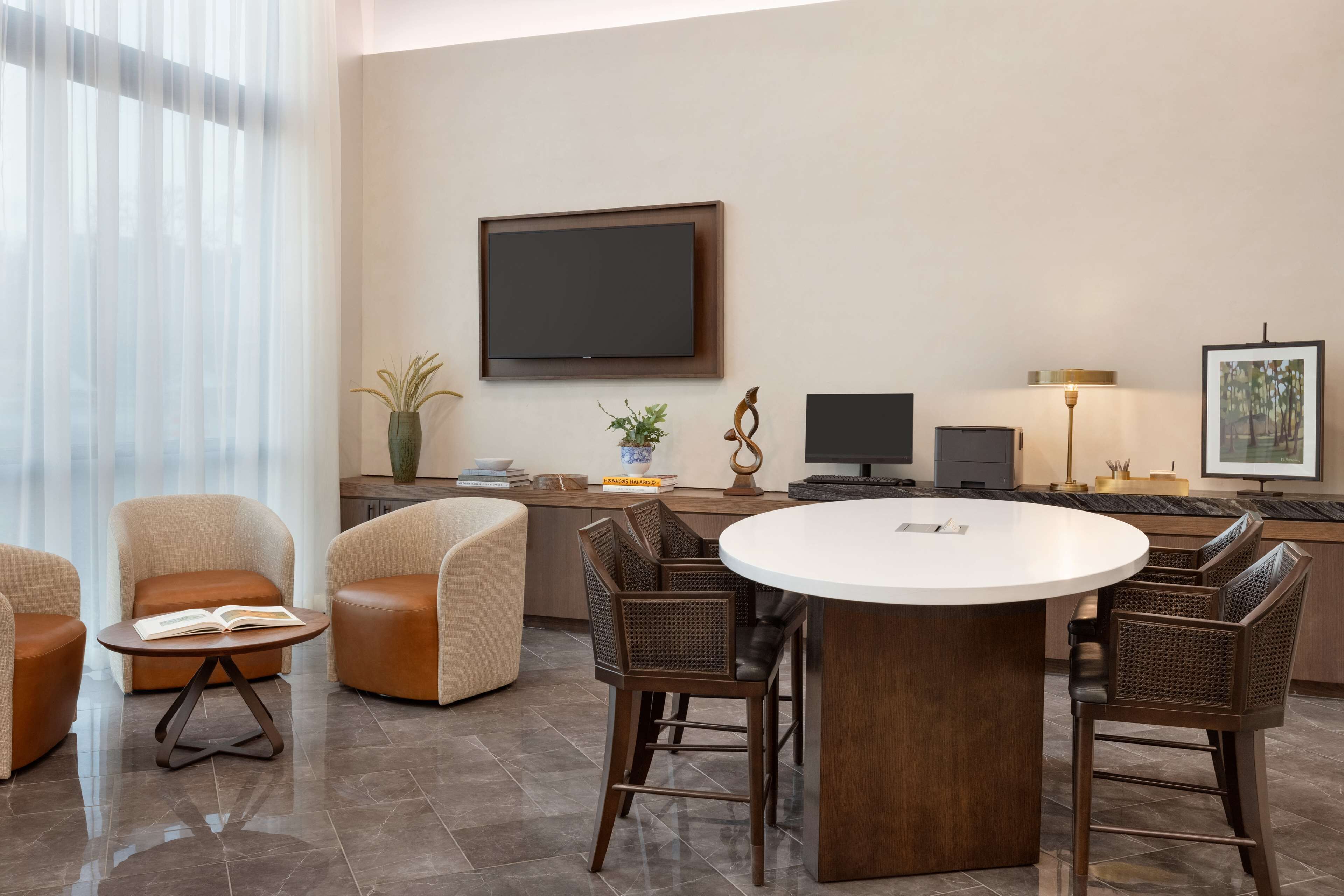 Un salon moderne avec une table à manger ronde, des sièges confortables, un téléviseur à écran plat et une table basse sur laquelle est posé un livre.