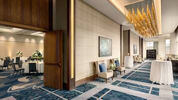 A hotel lobby with a patterned carpet, a large chandelier, and a seating area with a table and chairs.
