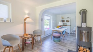 Een moderne keuken met een eethoek, houten vloeren en een ingebouwde houtkachel.