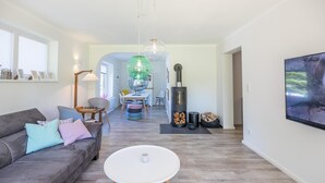 Een moderne woonkamer met een bank, een salontafel, een open haard en een eethoek.