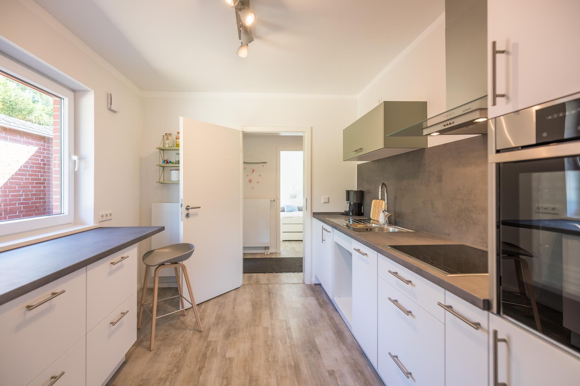 A modern kitchen with white cabinets, a wooden countertop, and a built-in oven.