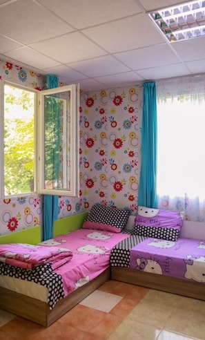 A room with two beds, a window, and a patterned wall.