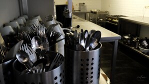 A kitchen with stainless steel utensils in holders, a stove, and a white tiled backsplash.