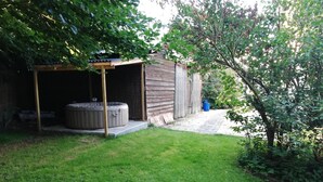 A wooden shed with a covered porch and a hot tub.