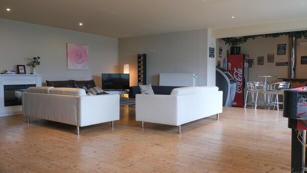 A modern living room with two white sofas, a flat-screen TV, and a fireplace.
