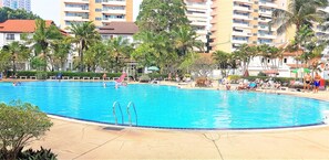 A large outdoor swimming pool surrounded by palm trees and buildings. - 11th Floor Studio at View Talay 1 (Pattaya)