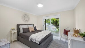 A bedroom with a bed, bedside table, and a view of the outdoors.