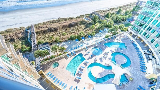 A resort with a large pool area, multiple lounge chairs, and a beach view. - 8th Floor with Stunning Views Contemporary Oceanfront (North Myrtle Beach)