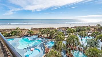 A resort with multiple swimming pools, a beach view, and palm trees.