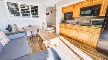 A compact kitchen with wooden cabinets, a microwave, a stove, and a sink.