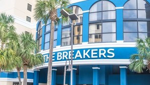 A building with a blue and white facade, the sign "THE BREAKERS" prominently displayed, and palm trees in front. - Oceanfront,Heated Pools,Views New, Penthouse Level (Myrtle Beach)