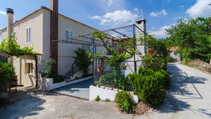 A residential property with a white exterior, a brick chimney, a metal pergola, and a gravel driveway. - Villa Dalmatian Gem (Konavle)