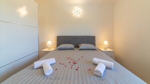 Una cama bien hecha con ropa de cama a rayas, dos almohadas, dos lámparas de noche y una lámpara en forma de estrella sobre la cama.