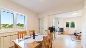 Un comedor amplio con una mesa de madera dispuesta para cuatro personas, una televisión y una chimenea al fondo.