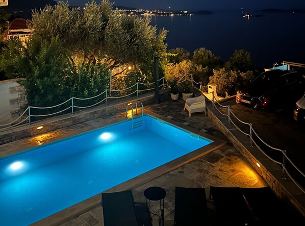 A swimming pool with a view of the sea at night. - Apartments Lavilla (Mlini)