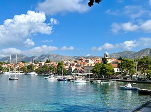 A coastal town with a marina, buildings with red roofs, and a mountain backdrop. - Apartments Lavilla (Mlini)