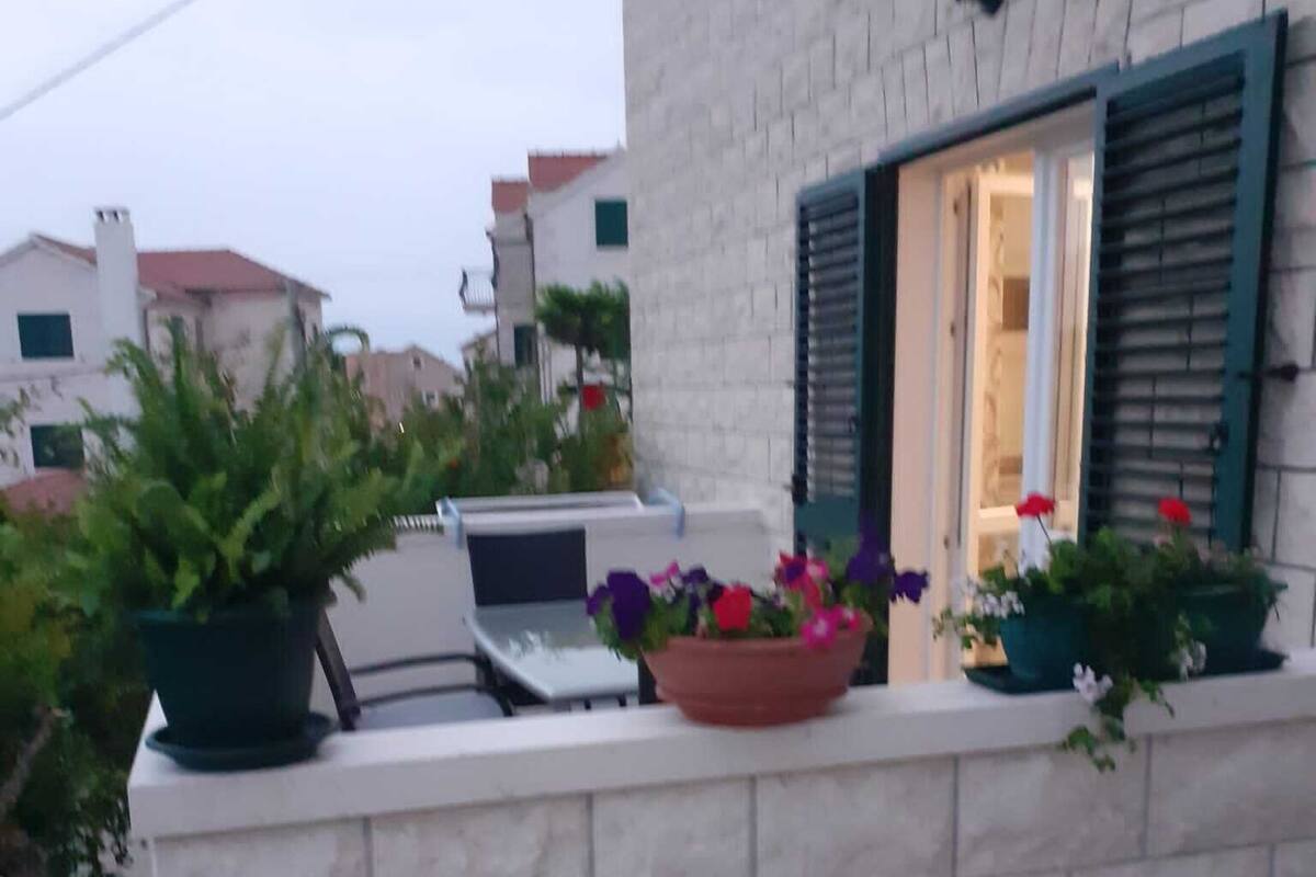 A balcony with a white brick wall, a laptop, and potted plants.
