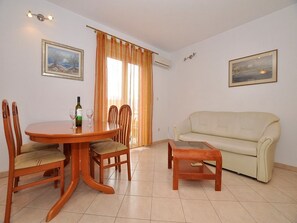 A dining area with a wooden table and chairs, a beige sofa, and two framed pictures on the walls. - Apartments Seagull (Postira)