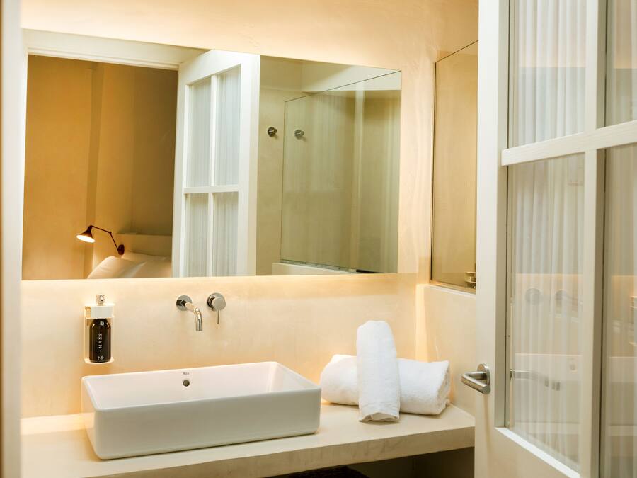 Un baño moderno con un espejo grande, un lavabo rectangular y una cabina de ducha de vidrio.