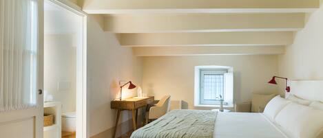 A bedroom with a bed, desk, chair, and a window.