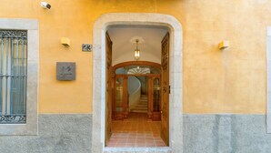 A hotel entrance with a stone archway, a staircase leading inside, and a sign with the number 23.
