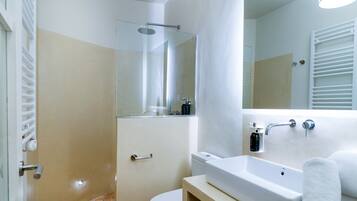 Une salle de bain moderne avec une douche à parois de verre, un lavabo blanc et des toilettes.