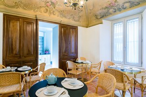 Un comedor con sillas de mimbre y una mesa redonda dispuesta para una comida, con tetera y platos.