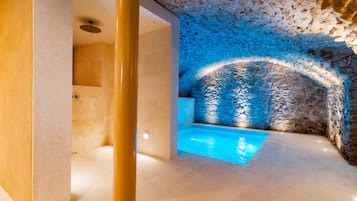 A spa area with a stone wall, a small pool, and a ceiling light.