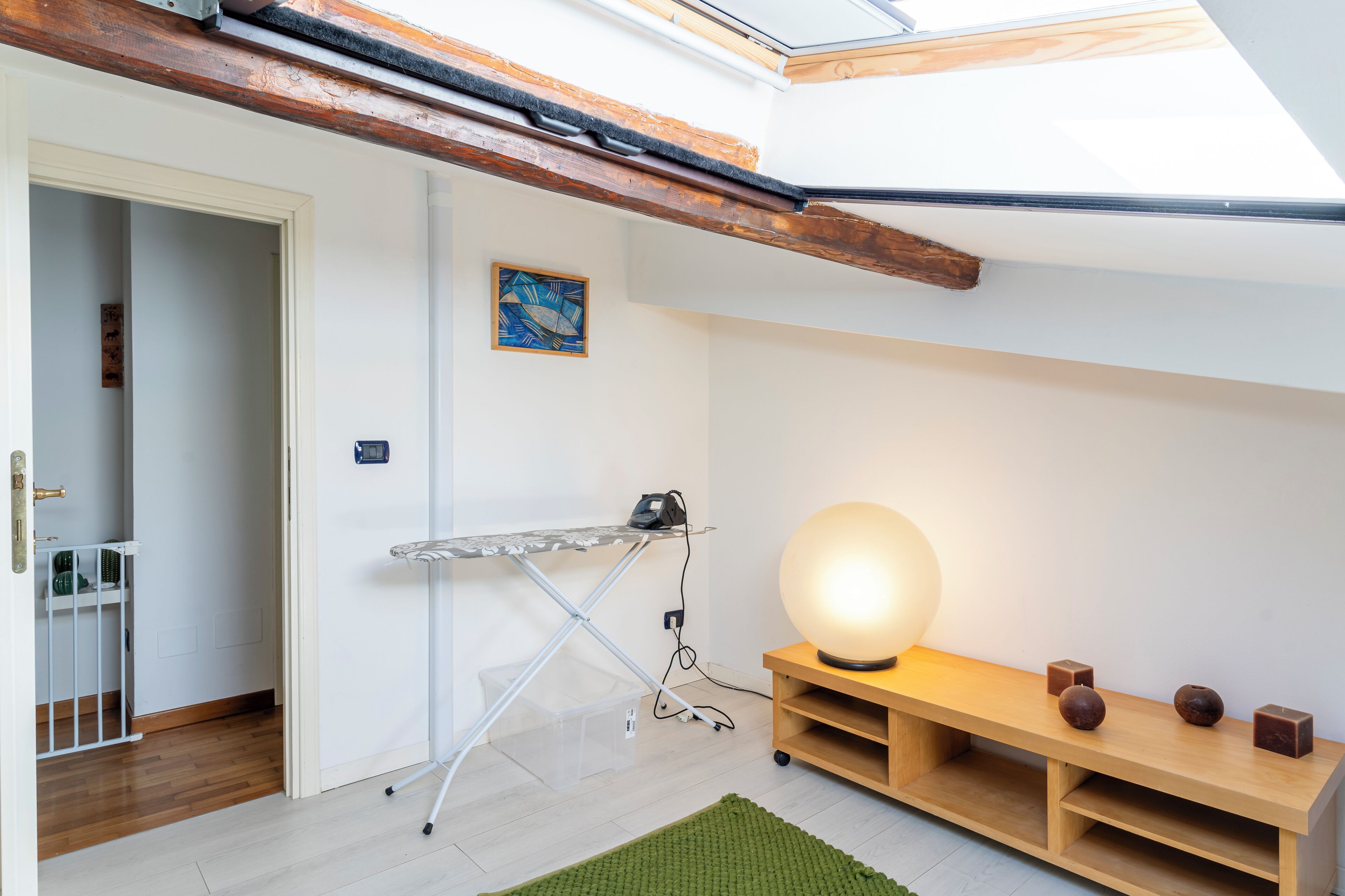 Una stanza con una panca in legno, un tavolo con una lampada e un piccolo ripiano con oggetti decorativi.