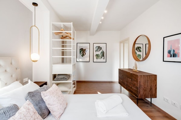 A modern bedroom with a bed, a wardrobe, a dresser, and wall art.