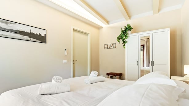 A hotel room with two beds, a large mirror, a framed picture on the wall, and a 'LOVE' sign. - Piazzale Michelangelo Modern Flat (Florence)