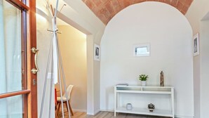 A room with a wooden door, a white console table with decorative items, and a chair. - Piazzale Michelangelo Modern Flat (Florence)