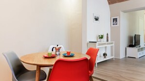 A dining area with a round wooden table, red chairs, and a white wall with a framed picture. - Piazzale Michelangelo Modern Flat (Florence)