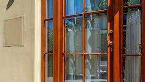 A wooden-framed door with a glass panel, a metal door handle, and a beige wall with a small square vent. - Piazzale Michelangelo Modern Flat (Florence)