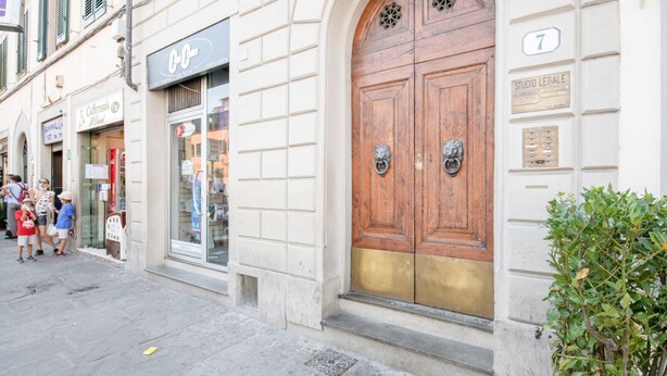 A street view with a café, a legal studio, and a traditional wooden door. - Piazza San Marco Studio Flat (Florence)