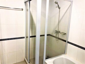 A glass-enclosed shower area with a handheld showerhead, a glass-enclosed bathtub, and a towel rack. - Platinum Suites Studio Condo Jomtien - Sleeps 2 (Pattaya)