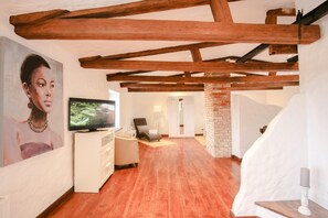 Relax in a spacious living area with a high ceiling, flat-screen TV, and comfortable seating.