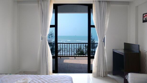 A bedroom with a large window, a bed, a TV, and a view of the ocean. - VITS Excellensea Karde Beach (Dapoli)