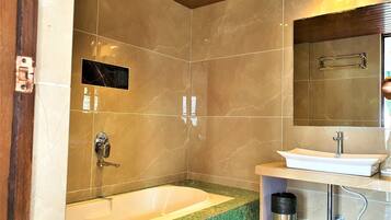 A bathroom with a bathtub, a sink, and a mirror.