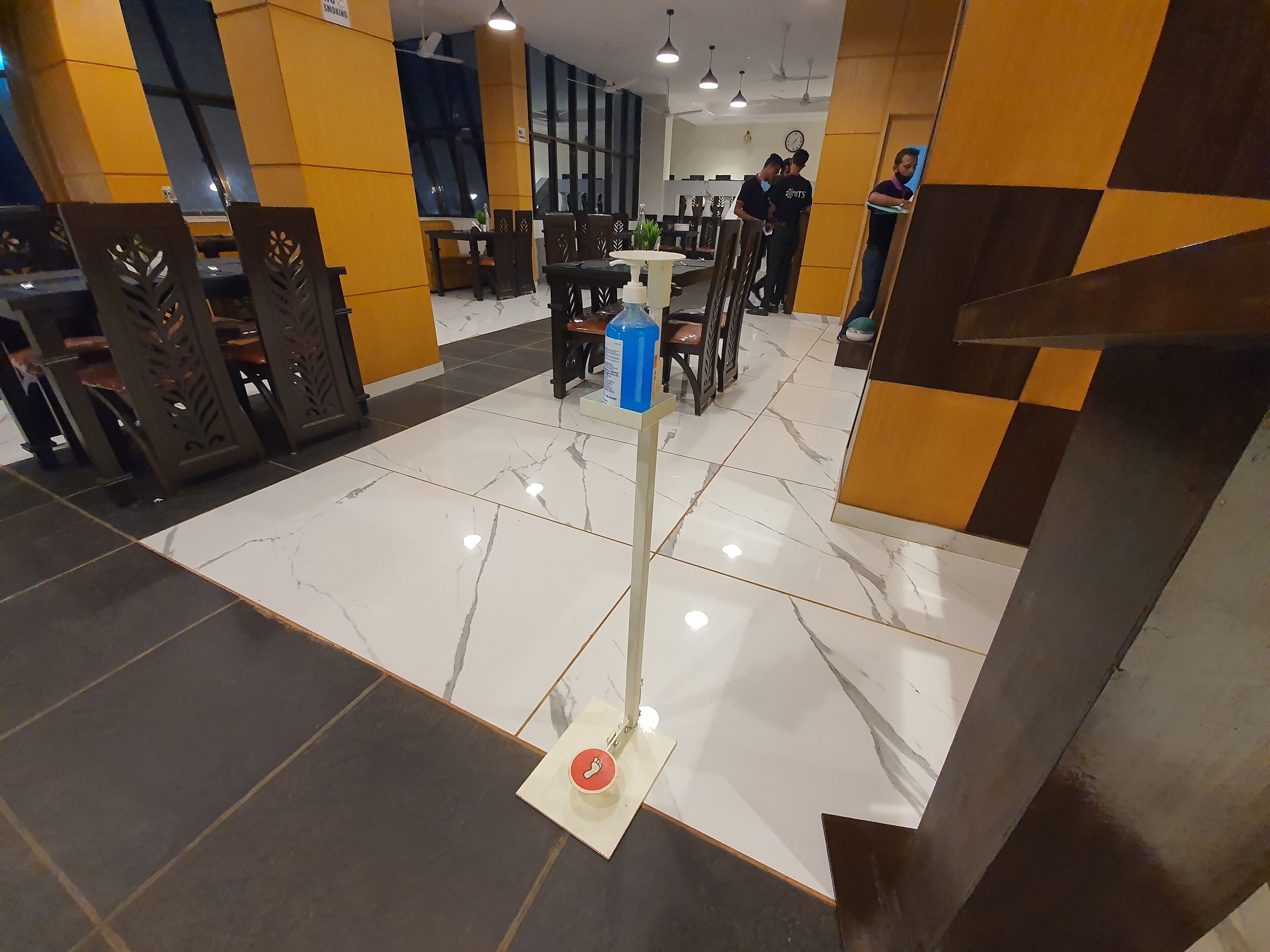 Un vestíbulo de hotel con piso de mármol, mobiliario de madera y un dispensador de agua azul.